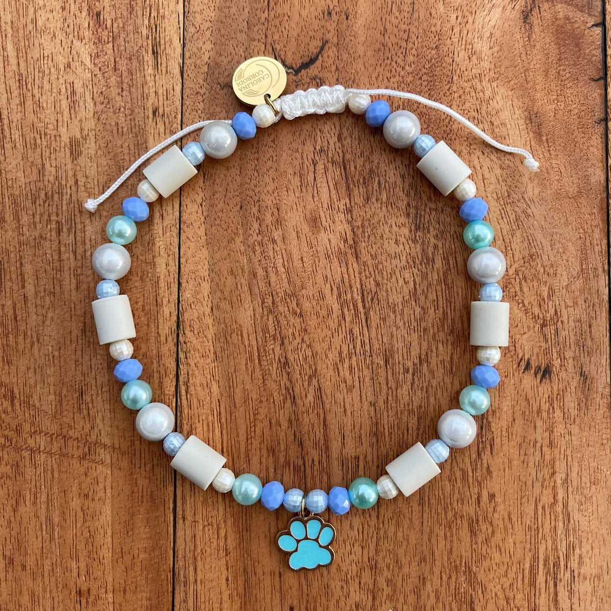EM-Keramikhalsband mit blauen Perlen und goldenem Anhänger mit blauer Pfote