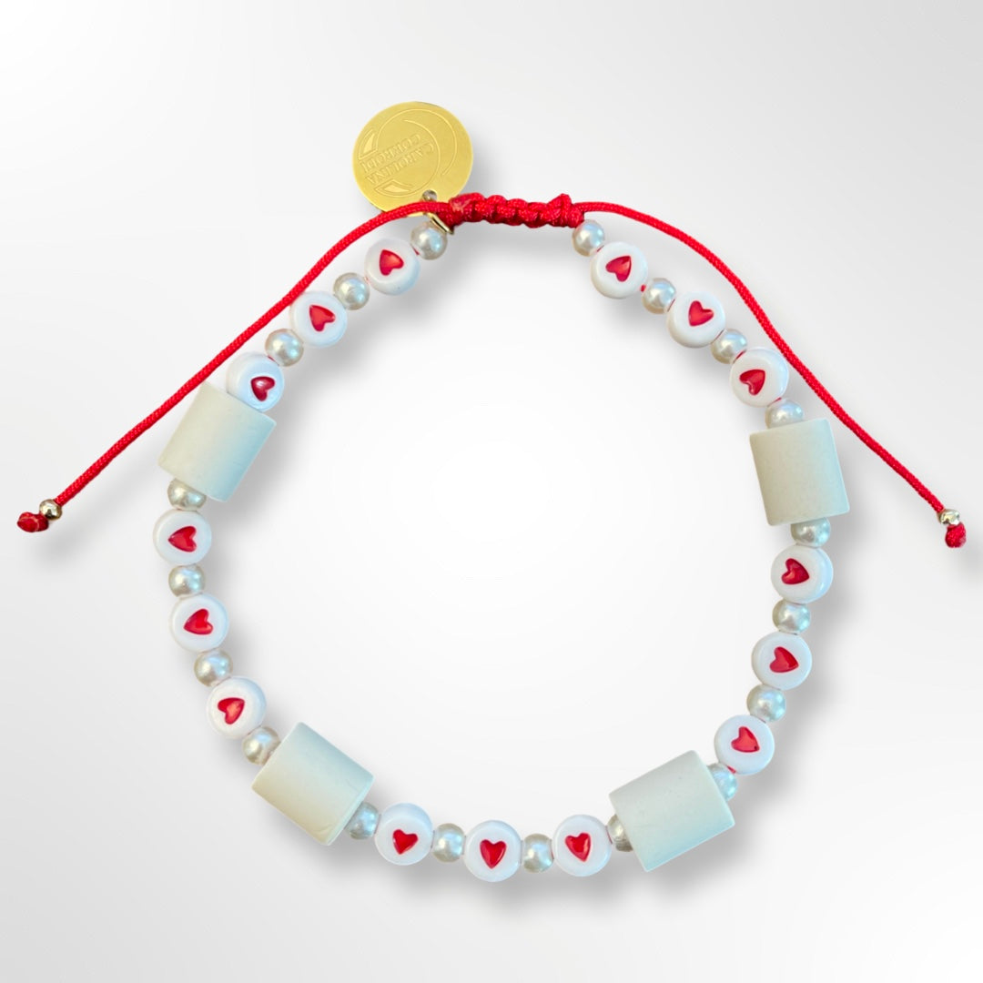 EM-Zeckenhalsband, weisse Perlen mit roten Herzen darauf mit rotem Faden und goldenem Logo.